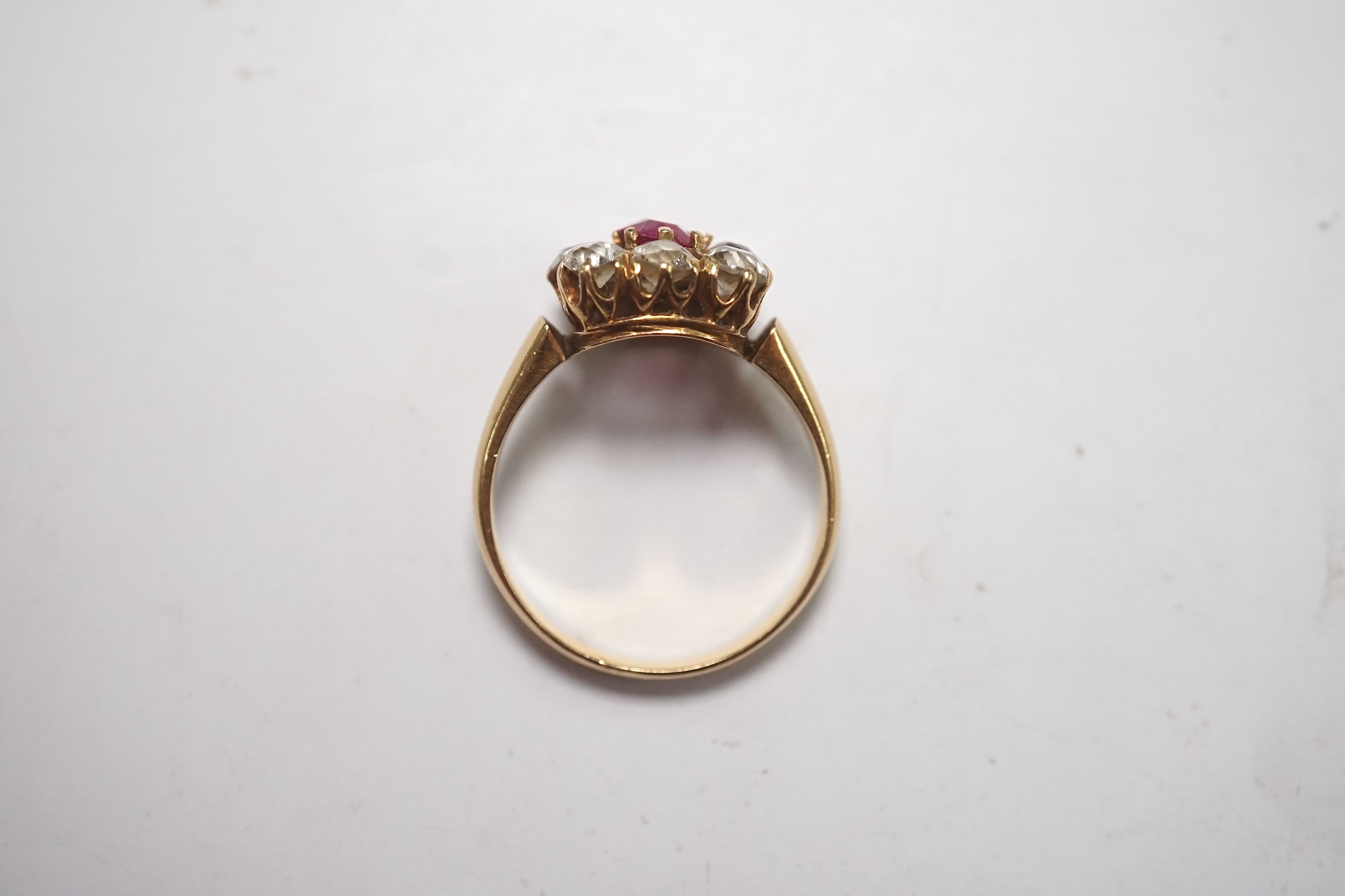 An early 20th century yellow metal, single stone ruby and eight stone diamond set square cluster ring, size O, gross weight 5 grams, one diamond missing. Condition - poor to fair